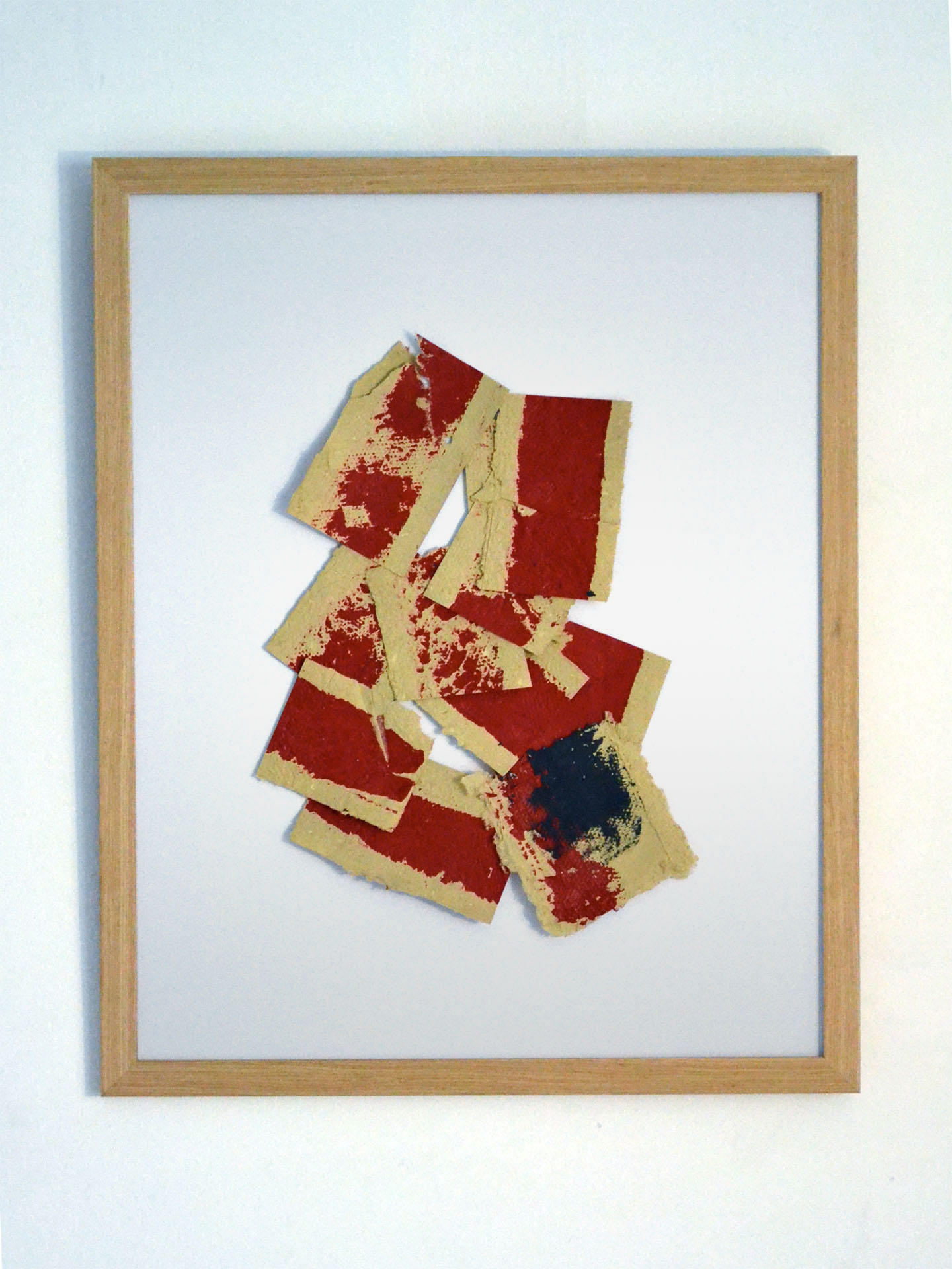 Obra original "Deconstruyendo II" enmarcada en madera natural con fondo blanco. Composición dinámica de fragmentos de papel artesanal ocre con manchas de pintura roja y una mancha negra central, creando un collage matérico y enérgico.