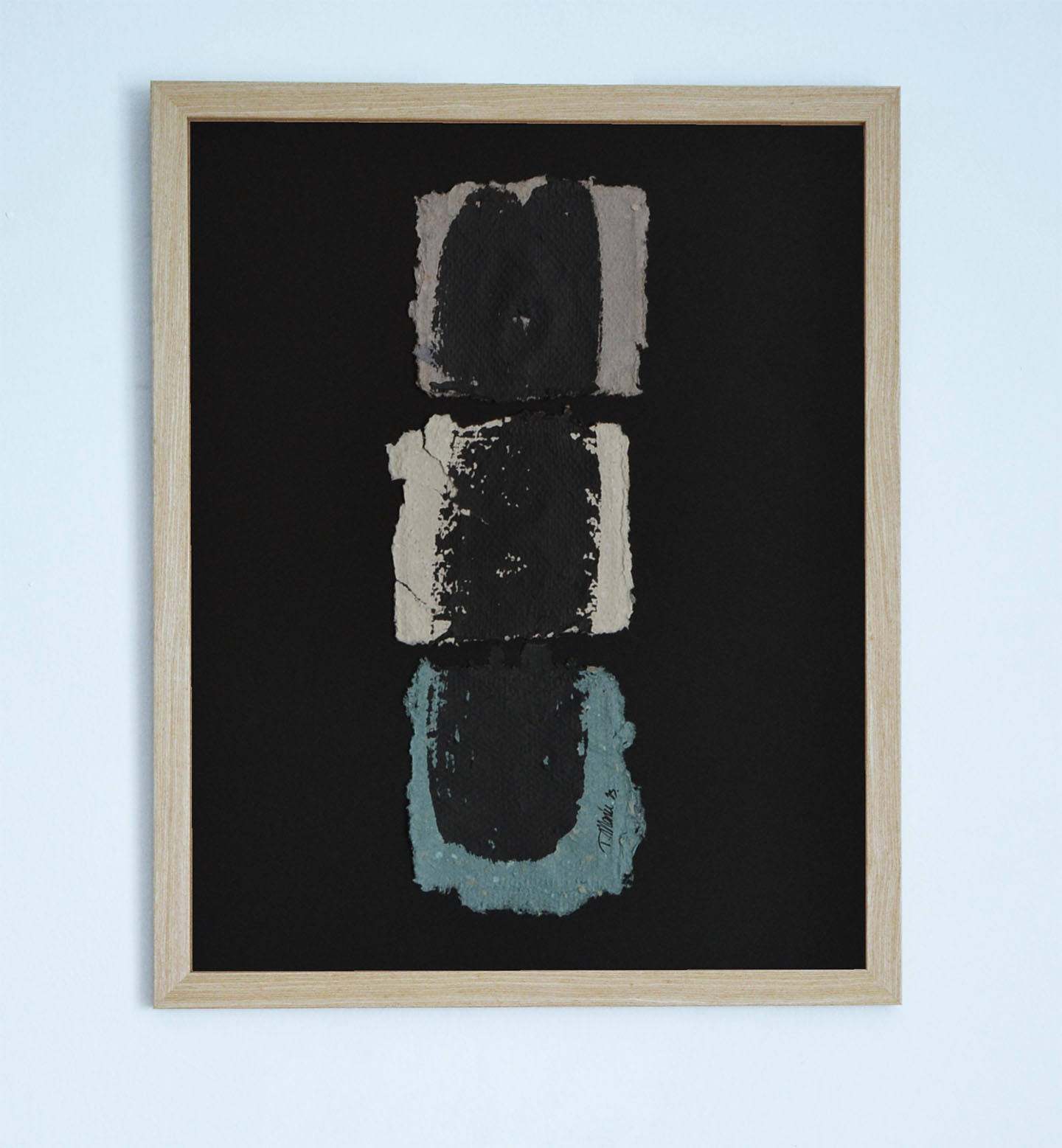 Obra original "Deconstruyendo III" enmarcada en madera clara con fondo negro. Composición vertical de tres piezas de papel artesanal con formas orgánicas en color topo, crema y azul agua, cada una con una mancha central negra y bordes irregulares.